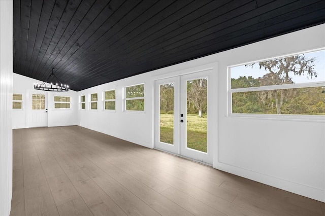 spare room featuring french doors, vaulted ceiling, wooden ceiling, a notable chandelier, and hardwood / wood-style floors