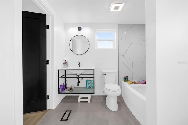 bathroom with tile patterned flooring, a tub to relax in, toilet, and sink