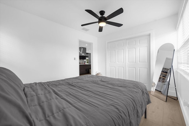 bedroom with ceiling fan, light hardwood / wood-style floors, and a closet