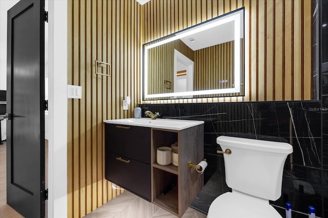 bathroom featuring vanity, toilet, and tile walls