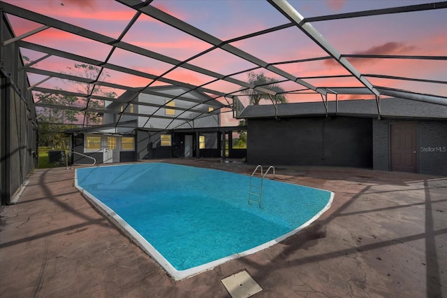 pool at dusk with a lanai and a patio