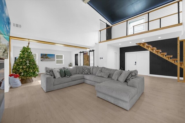 living room featuring a barn door, light hardwood / wood-style floors, and a high ceiling