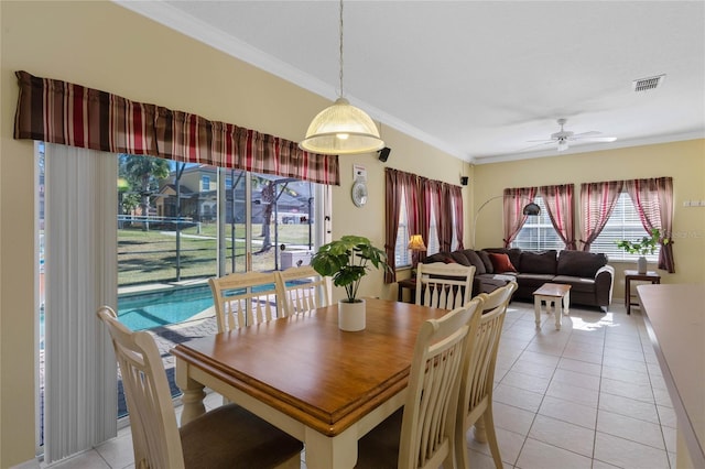 dining space with ceiling fan, crown molding, and light tile patterned flooring