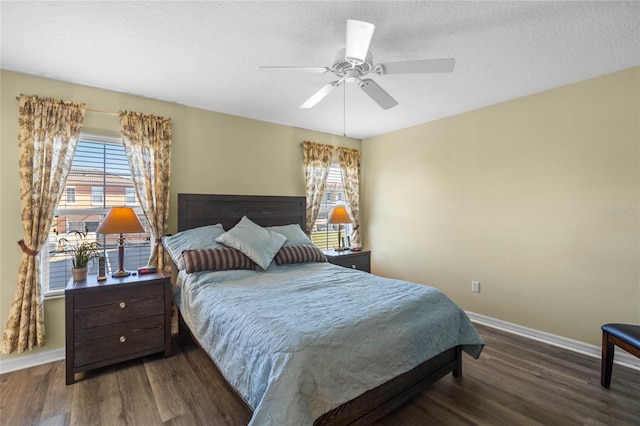 bedroom with a textured ceiling, multiple windows, dark wood-type flooring, and ceiling fan