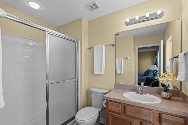 bathroom with an enclosed shower, vanity, toilet, and a textured ceiling