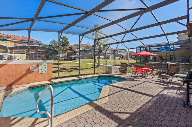 view of pool featuring a lawn, a patio area, and a lanai