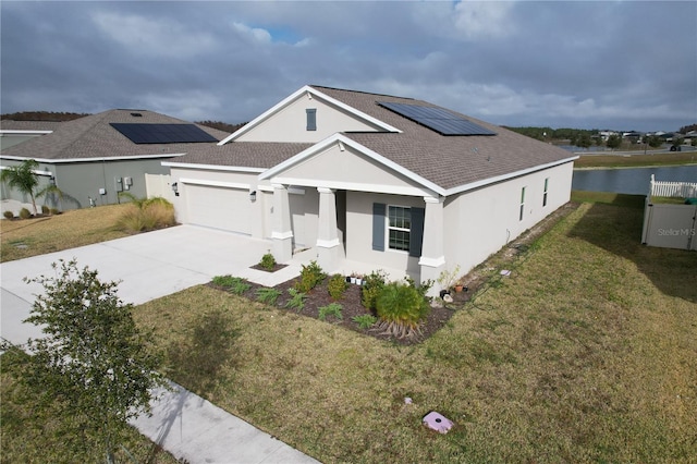 view of front of property featuring solar panels, a front lawn, a garage, a water view, and a porch