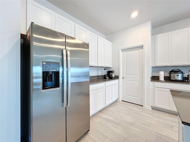 kitchen with stainless steel fridge, light hardwood / wood-style flooring, and white cabinets