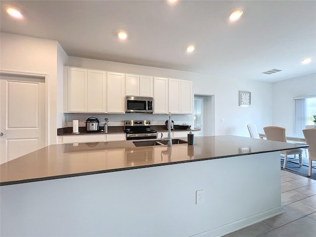 kitchen featuring white cabinets, sink, appliances with stainless steel finishes, and an island with sink