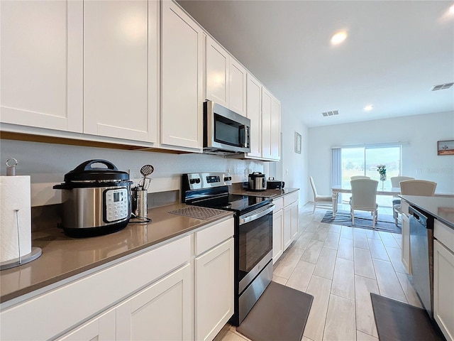 kitchen with light hardwood / wood-style flooring, white cabinets, and stainless steel appliances