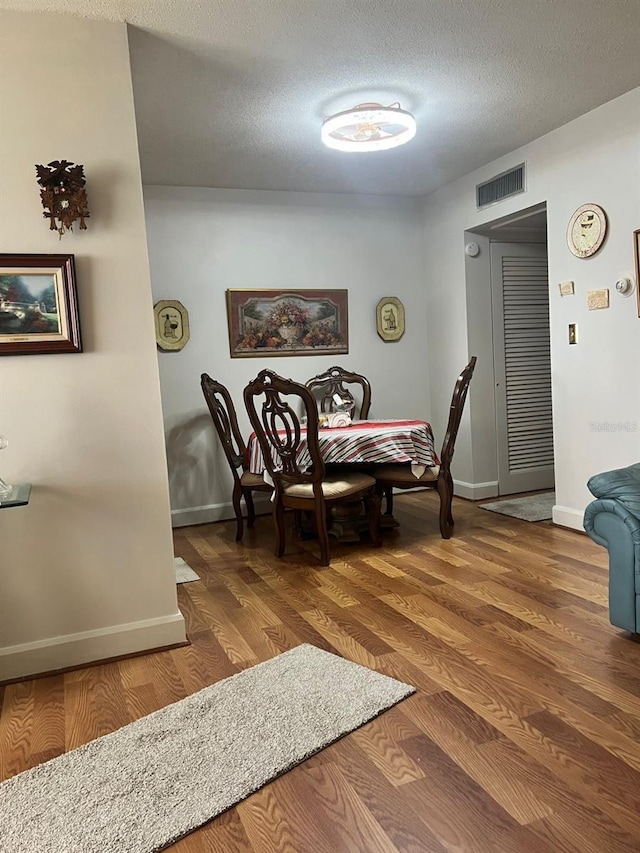 dining area with a textured ceiling and dark hardwood / wood-style flooring