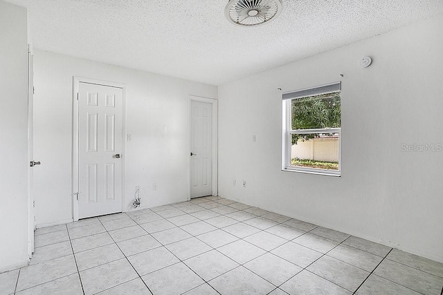 tiled spare room with a textured ceiling