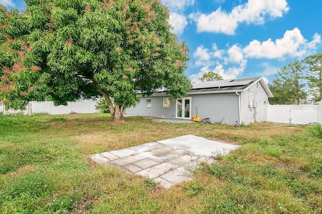 back of property featuring a yard, a patio, and solar panels