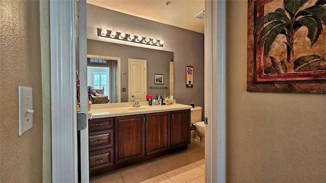 bathroom featuring tile patterned flooring, a textured ceiling, vanity, and toilet