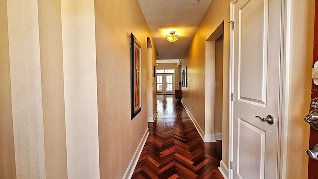 hallway with a textured ceiling and dark parquet floors