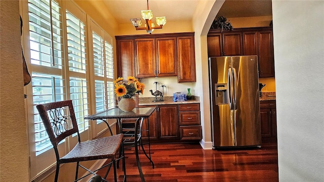 kitchen with a wealth of natural light, stainless steel fridge, light stone counters, and dark hardwood / wood-style floors