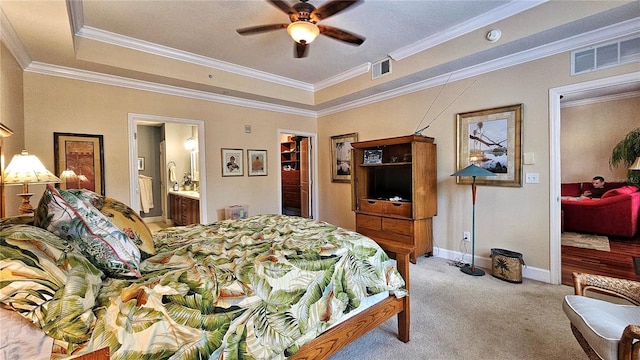 bedroom with ensuite bath, a tray ceiling, ceiling fan, crown molding, and a spacious closet