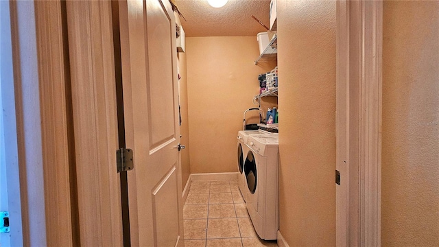 clothes washing area featuring light tile patterned flooring, a textured ceiling, and washing machine and clothes dryer