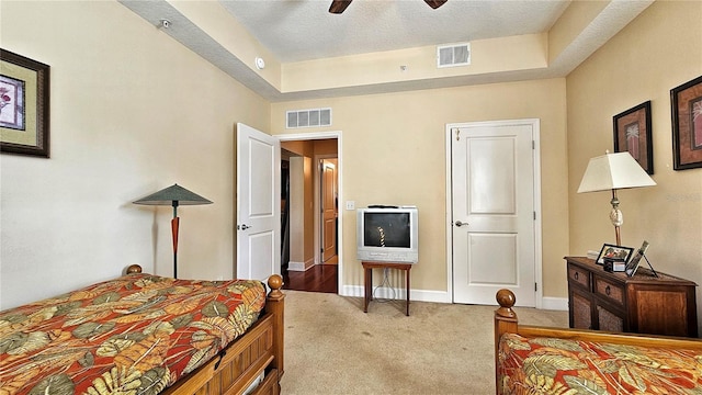 bedroom with a raised ceiling, ceiling fan, carpet, and a textured ceiling