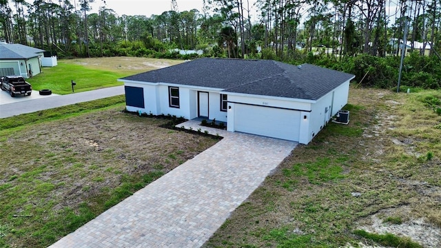 view of front of house with central air condition unit, a front lawn, and a garage