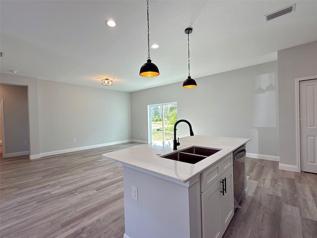 kitchen with white cabinets, a kitchen island with sink, sink, pendant lighting, and dishwasher