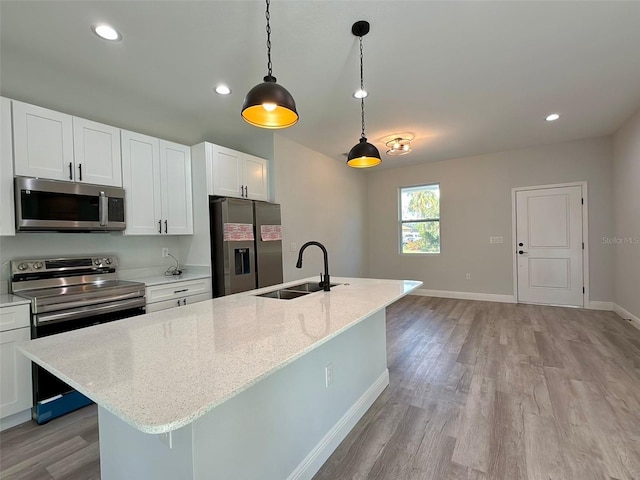 kitchen featuring stainless steel appliances, sink, pendant lighting, a center island with sink, and white cabinets