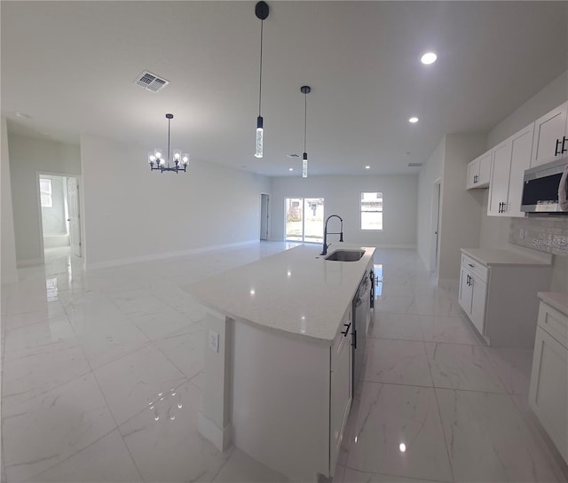 kitchen with sink, stainless steel appliances, decorative light fixtures, a center island with sink, and white cabinets