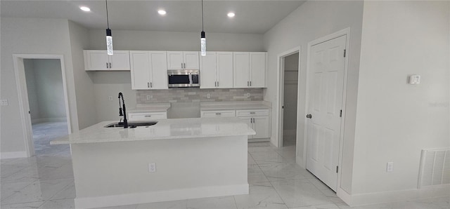 kitchen featuring decorative light fixtures, sink, and a kitchen island with sink