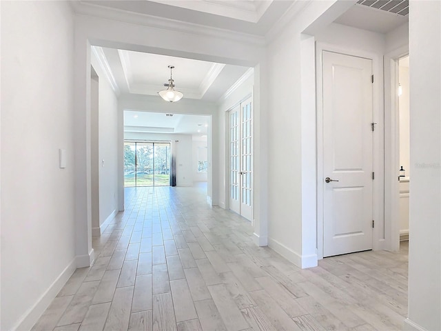 corridor featuring a raised ceiling, crown molding, and light wood-type flooring