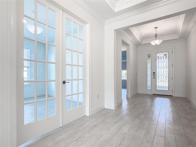 foyer entrance with a raised ceiling, ornamental molding, french doors, and light hardwood / wood-style flooring