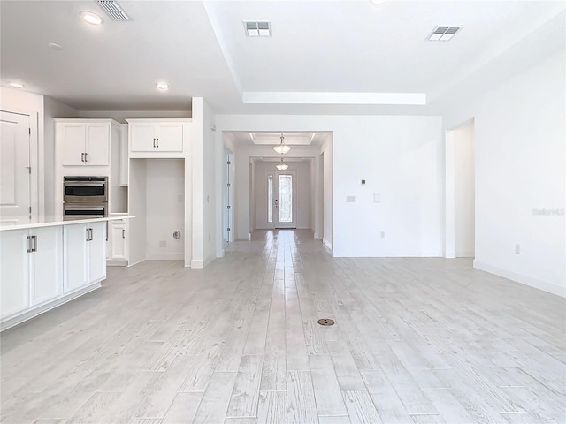 kitchen featuring white cabinetry, stainless steel double oven, and light hardwood / wood-style floors