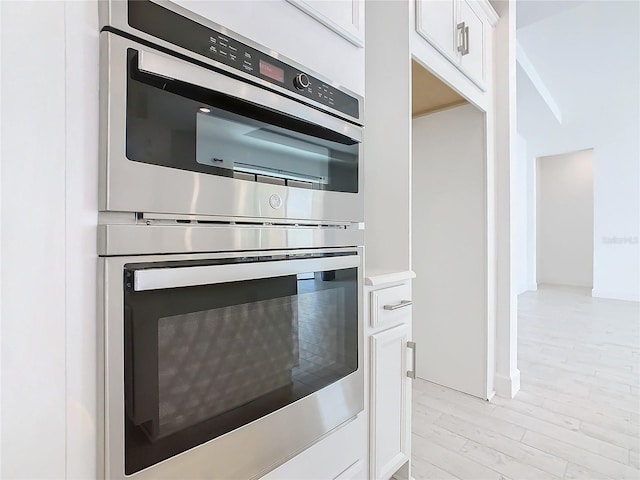 details featuring white cabinets, double oven, and light hardwood / wood-style flooring