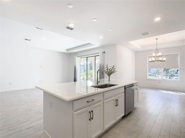 kitchen featuring white cabinetry, sink, stainless steel dishwasher, a kitchen island with sink, and light wood-type flooring