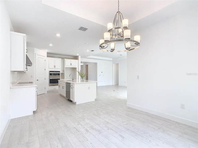 kitchen featuring white cabinetry, an island with sink, light wood-type flooring, and an inviting chandelier