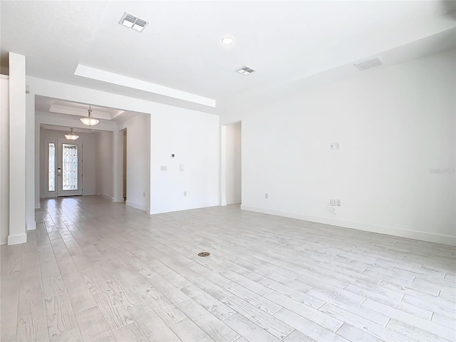 spare room featuring a tray ceiling, french doors, and light hardwood / wood-style floors