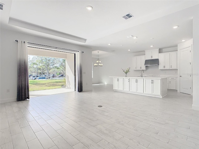 unfurnished living room featuring a chandelier, light wood-type flooring, and sink