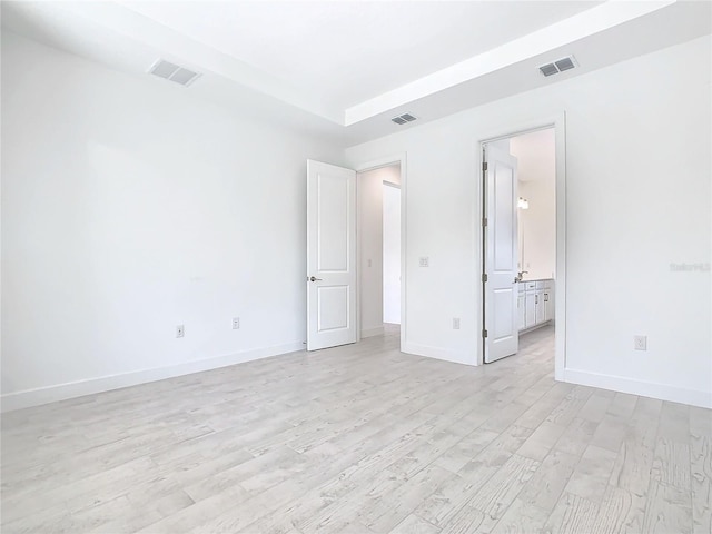 unfurnished bedroom with light hardwood / wood-style floors and ensuite bath