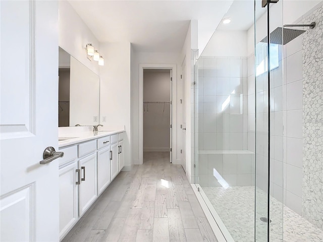 bathroom with hardwood / wood-style floors, vanity, and a tile shower