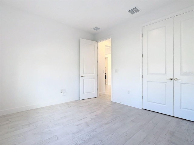 unfurnished bedroom with light wood-type flooring and a closet