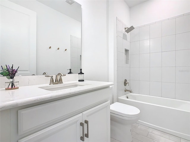 full bathroom featuring tiled shower / bath combo, toilet, and vanity