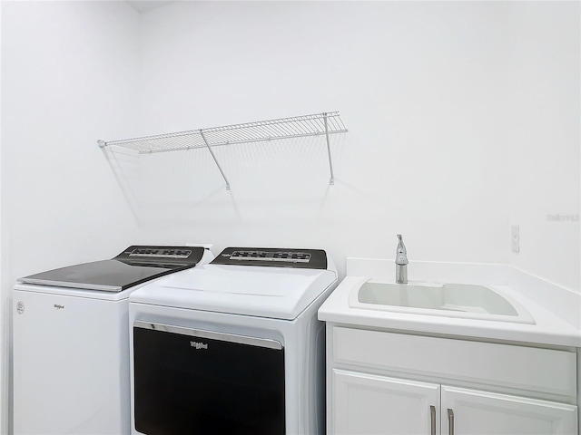 clothes washing area featuring cabinets, sink, and washer and dryer