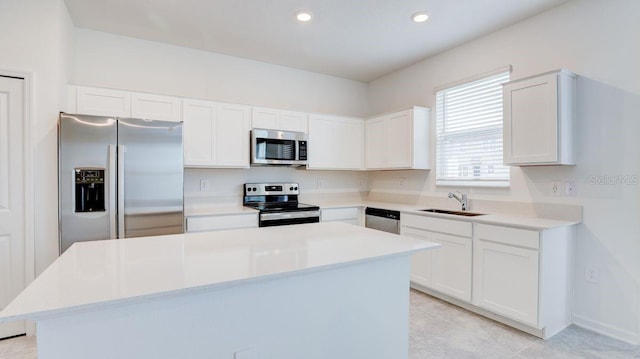 kitchen with sink, stainless steel appliances, a kitchen island, white cabinets, and light tile patterned flooring