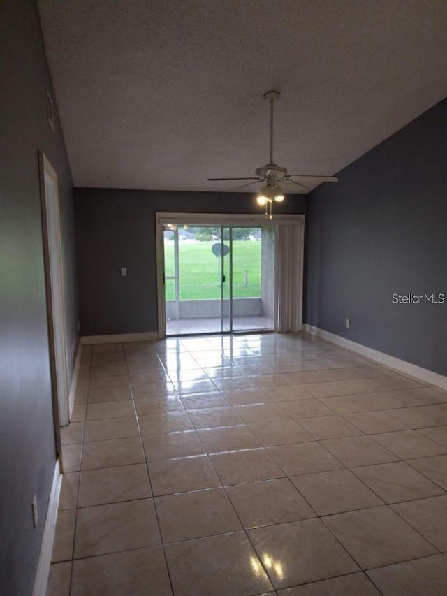 spare room featuring a textured ceiling, vaulted ceiling, ceiling fan, and light tile patterned flooring