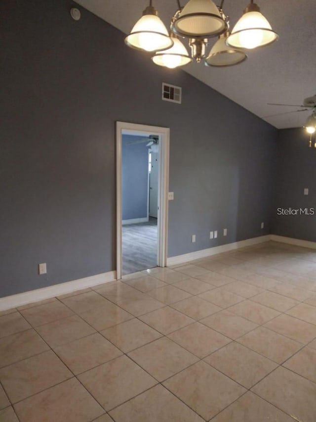 empty room with light tile patterned floors, ceiling fan with notable chandelier, and vaulted ceiling