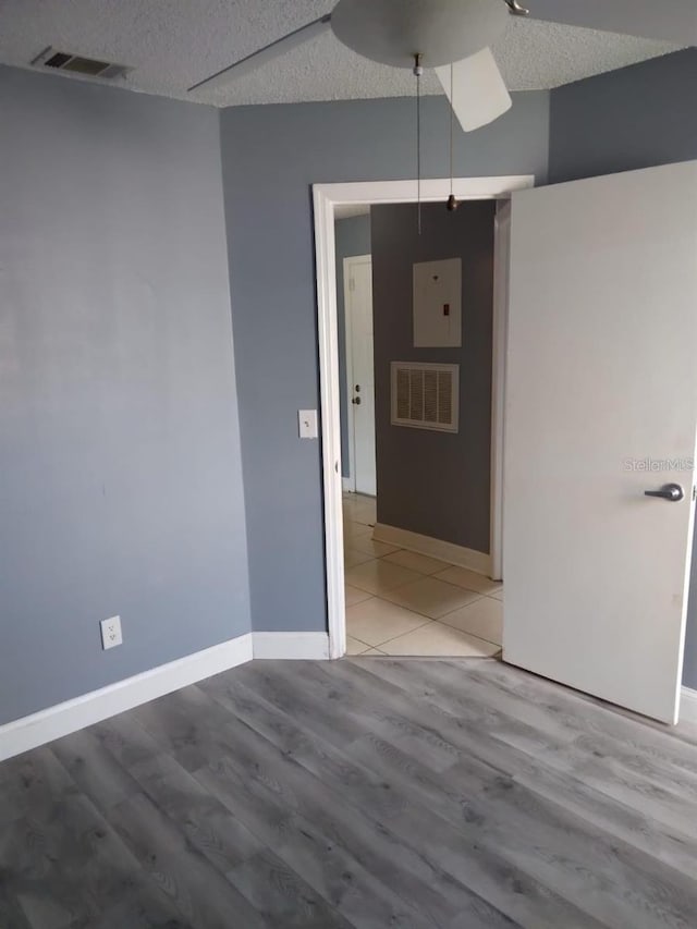 unfurnished room with a textured ceiling and light wood-type flooring