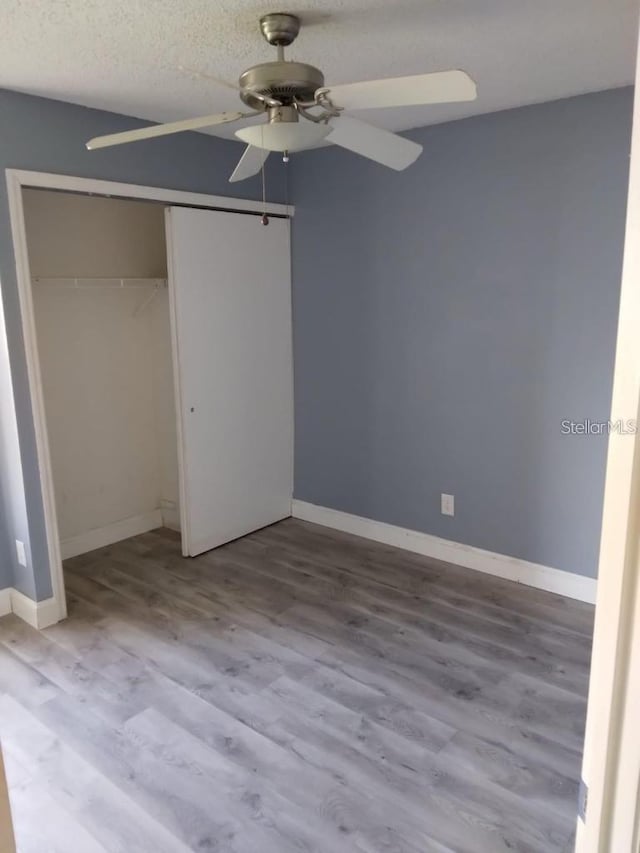 unfurnished bedroom featuring a closet, ceiling fan, a textured ceiling, and light hardwood / wood-style flooring