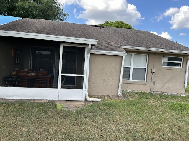 rear view of property featuring a yard and a sunroom