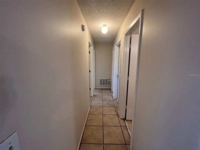 corridor with light tile patterned floors and a textured ceiling