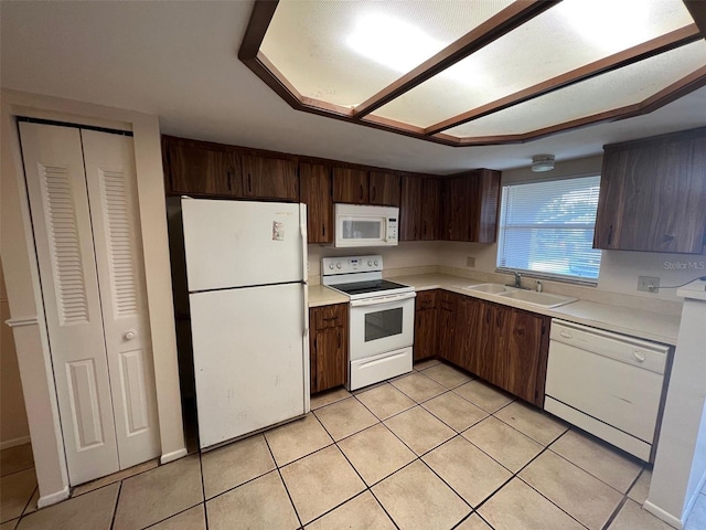 kitchen with dark brown cabinets, white appliances, sink, and light tile patterned floors