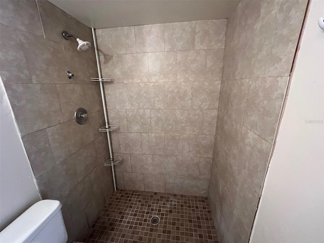 bathroom featuring a tile shower and toilet